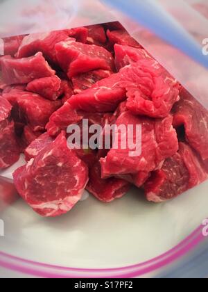 Close up of sirloin beef chunks in Ziploc bag on cutting board USA Stock Photo