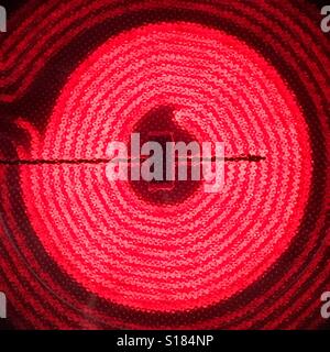 Circular heating element on a glass top stove glowing red Stock Photo