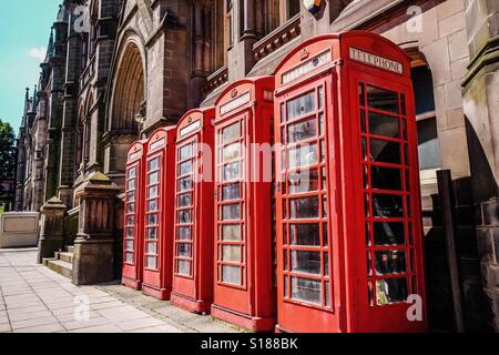 Row of four traditional British telephone boxes (booths) outside the Victorian Town Hall in Middlesbrough, UK with text space and no people. Stock Photo