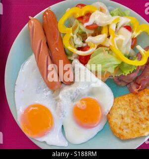 Breakfast- fried sausages, eggs, bacon, hash brown and salad Stock Photo