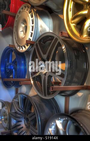 Brightly coloured alloy wheel hubs hanging on a workshop display rack. Stock Photo