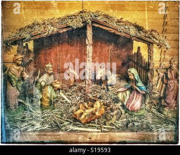 A grunge effect picture of a model of the Christmas Nativity Scene. The baby Jesus is in his crib, surrounded by Mary, Joseph, cows & The Tree Wise Men bearing gifts. Photo Credit - © COLIN HOSKINS. Stock Photo