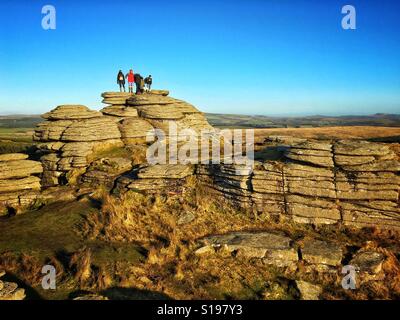 A group of walkers enjoys the view from atop Bellever Tor near Postbridge in Dartmoor National Park, Devon, UK Stock Photo