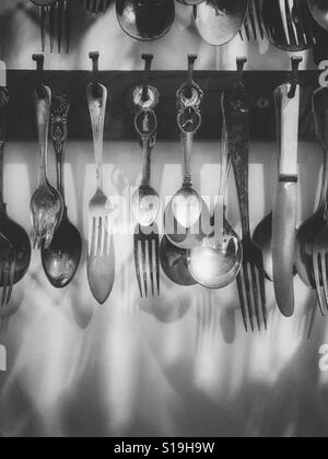 Knives, forks and spoons hanging on a wall Stock Photo