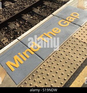 Mind the gap warning painted on railway station platform Stock Photo