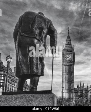 Black and white photo of the bronze statue of Sir Winston Churchill overlooking Big Ben in Parliament Square, London, UK. Stock Photo