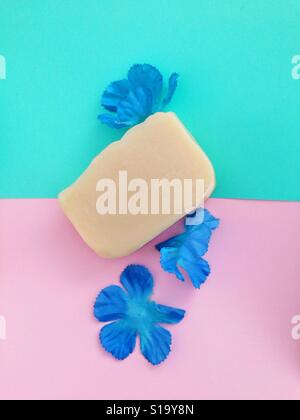 White bar soap on teal and pink background with blue flowers. Stock Photo