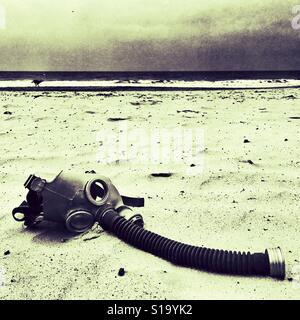 Gas mask discarded on a beach Stock Photo