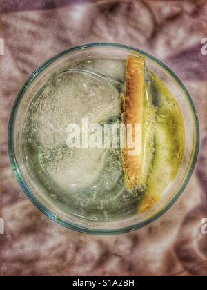 Glass with ice, lemon and clear, fizzy liquid, from above Stock Photo