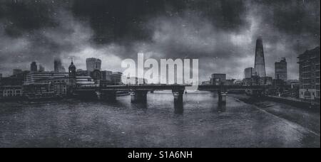 Dramatic black and white photo of the skyline over the River Thames, looking towards the Shard and Tower bridge, on a stormy foggy day in London, England, UK. Stock Photo