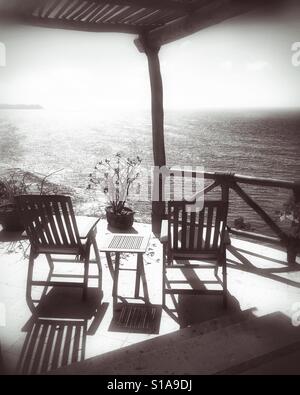 Sunlight and shadows add beauty and depth to the patio filled with teak furniture overlooking the Pacific Ocean in Nayarit, Mexico. Stock Photo