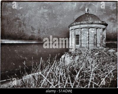 A moody & atmospheric monochrome image of Mussenden Temple, near Castlerock in Co. Londonderry, Northern Ireland. This is a small circular building located on a cliff edge above The Atlantic Ocean. Stock Photo