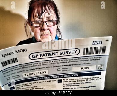 Woman reading an Ipsos Mori NHS GP patient survey form Stock Photo