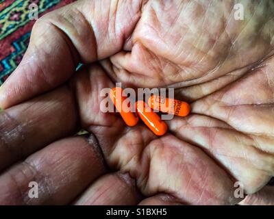 Strong opioids, three 12 mg capsules in the palm of a senior. Potent analgesic. Conceptual image suggesting possible addiction, dependence, overdosing, besides pain management. Stock Photo