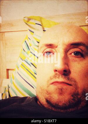 A portrait of a man sat up in bed. Stock Photo