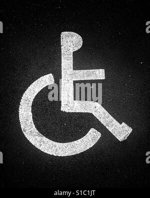 White painted road marking sign for a disabled parking bay depicting a stick figure in a wheelchair. Stock Photo