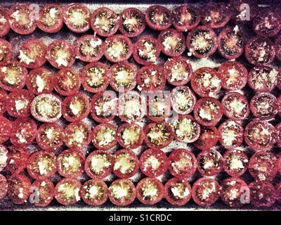 Cherry tomatoes, cut in half and topped with garlic ready to be roasted in the oven Stock Photo