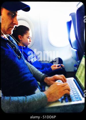 Father and daughter using technology on airplane Stock Photo