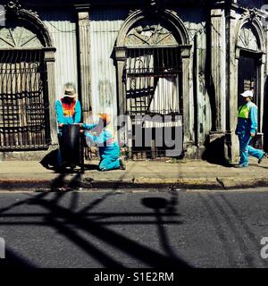 Salvadoran garbage collectors work in front of a ruined house, designed by using bold Spanish colonial architecture elements, built in the center of San Salvador, El Salvador, 10 November 2016. Stock Photo