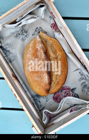 A loaf of artisanal bread in a rustic bread basket.