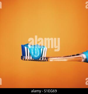 Single toothbrush with toothpaste against a yellow background. Stock Photo