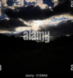Sun shining behind clouds Stock Photo