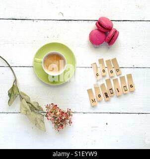 Lovely tabletop composition with cup of coffee, flowers, macarons and good morning quote Stock Photo