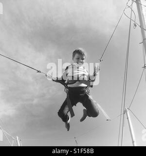 Boy jumping on elastic rope Stock Photo