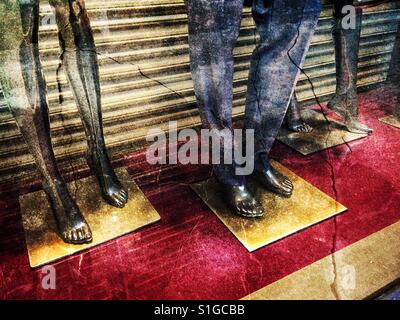 Male and female mannequin legs in cracked shop display window Stock Photo