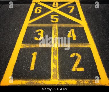 Numbers one through eight painted in yellow on a hopscotch game board on cement Stock Photo