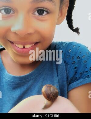 Young girl playing with a snail. Stock Photo