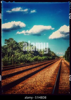 Triplets- Three clouds make their way across some railroad tracks. Stock Photo