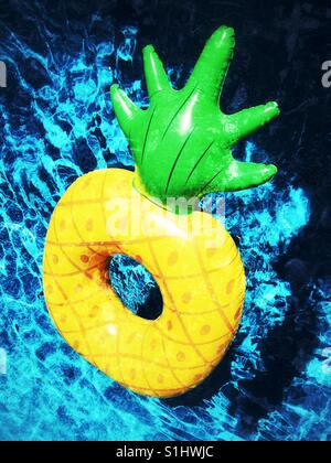 Pineapple pool toy floating on swimming pool water. Square crop Stock ...