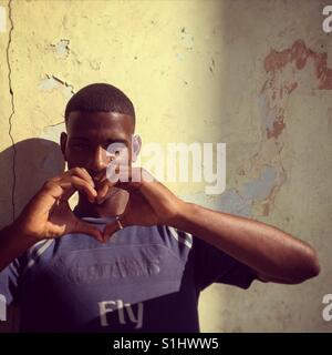 Young Cuban man making a heart shape with his hands Stock Photo