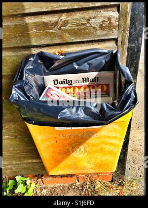 Tabloids dumped into a public bin. Stock Photo