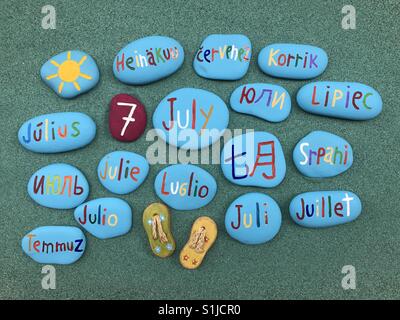 7 July, calendar date in many languages and colored stones over green sand Stock Photo