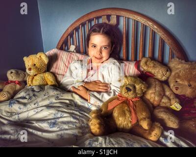 5-year old girl in bed with teddy bears Stock Photo