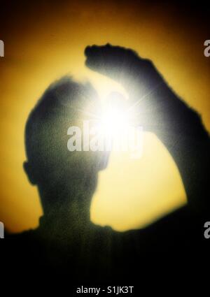 Man shading eyes an looking into the sun Stock Photo