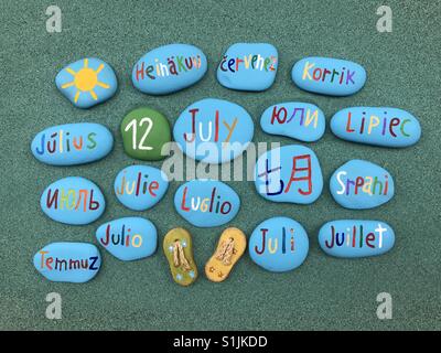 12 July, calendar date in many languages on colored stones over green sand Stock Photo