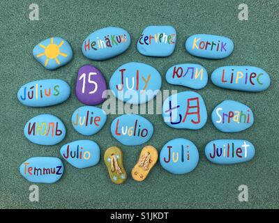15 July, calendar date in many languages on colored stones over green sand Stock Photo