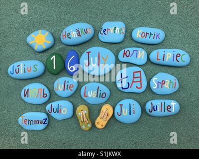 16 July, calendar date in many languages on colored stones over green sand Stock Photo