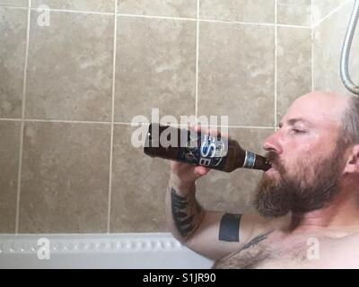 Man in hot bath drinking a beer from the bottle. Stock Photo