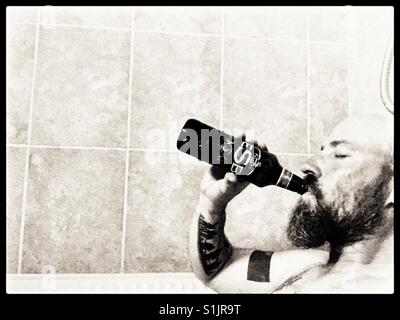 Man in hot bath drinking real ale from the bottle. Stock Photo