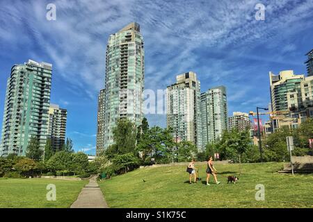 Two women walk a dog around the modern apartments of Yaletown, Canada. Stock Photo