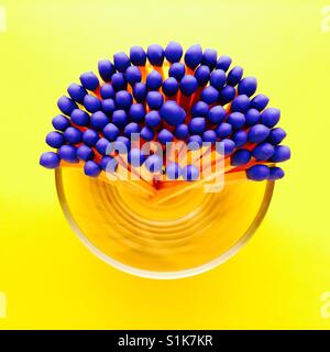 An overhead shot of a glass container half full of blue tipped matchsticks Stock Photo