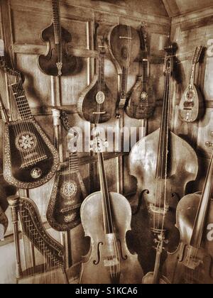 A collection of stringed musical instruments are kept in the corner of an old house somewhere in England. Guitars, harps & violins are all present. Photo Credit - © COLIN HOSKINS. Stock Photo