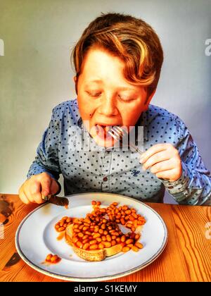 11-year old boy eating beans on toast Stock Photo