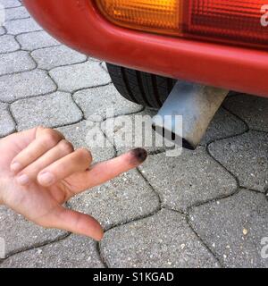 Smut from car exhaust pipe on finger Stock Photo