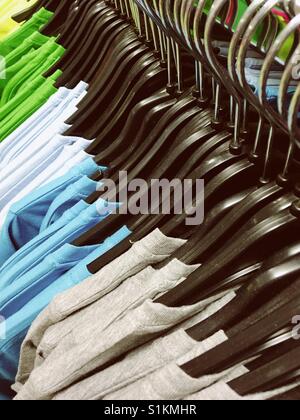 Colourful T-shirts on hangers for sale in a store Stock Photo