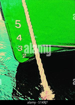 Ship's draft on green hull of moored ship. The vertical distance between the waterline and the bottom of the hull. Stock Photo